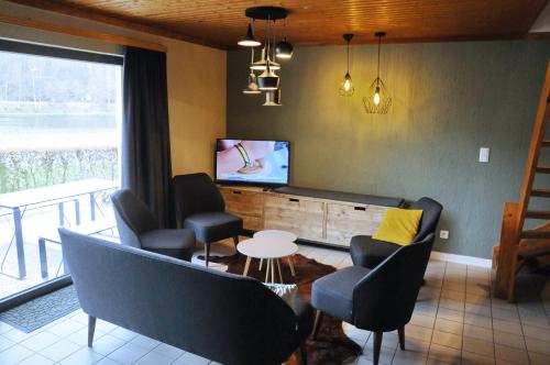 a living room with chairs and a tv and a table at Maison du Lac 14 in Vielsalm