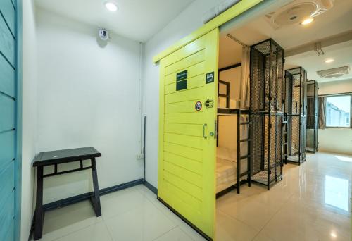 a room with a green door and a table at Sloth Hostel Don Mueang in Ban Don Muang