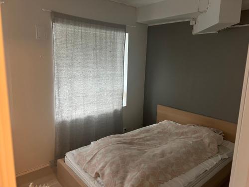 - une chambre avec un lit et une fenêtre avec une couverture dans l'établissement Ved sjøkanten, Ålesundsvegen 1068, à Ålesund