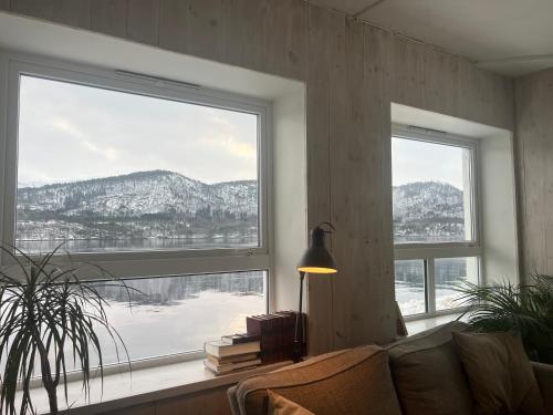 a living room with a couch and two large windows at Ved sjøkanten, Ålesundsvegen 1068 in Ålesund