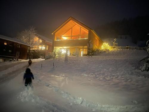 a person walking in the snow in front of a house at Zu Gast bei den Hagspiels in Hittisau
