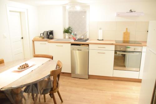 une cuisine avec des armoires blanches et une table avec des chaises dans l'établissement La Petite Maison de la Petite Vallée, à Rott