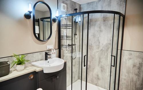 a bathroom with a shower with a sink and a mirror at The Retreat in Ainstable