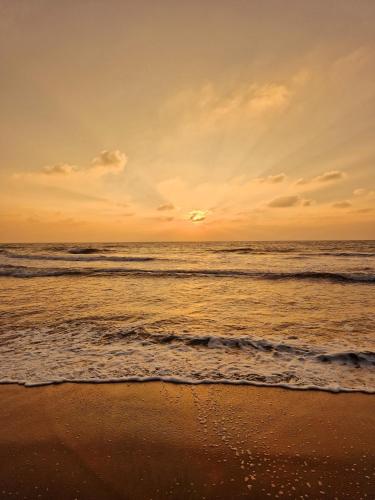 a sunset over the ocean on a beach at Nature Paradise Guesthouse in Waikkal