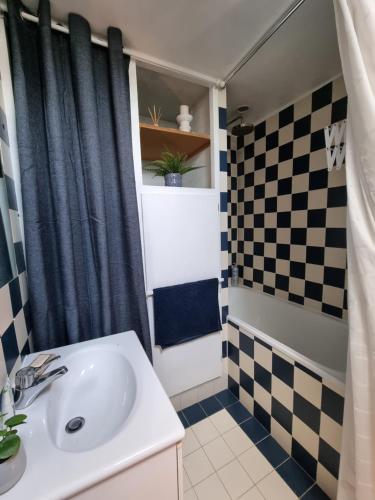 a bathroom with a sink and a checkered shower curtain at Charmant studio proche du château in Versailles