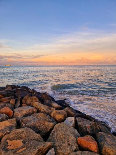 a group of rocks on the ocean at sunset at Nature Paradise Guesthouse in Waikkal