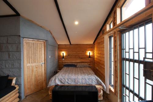 a bedroom with a bed in a room with windows at Elwai Centre Wood Cabins - Couples' hideout in Heni Village