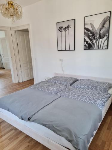 a bed in a white bedroom with a chandelier at Traumhafter Altbau im Herzen Schwertbergs in Schwertberg