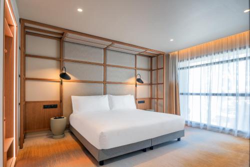 une chambre avec un grand lit blanc et une fenêtre dans l'établissement Résidence Les Embruns & Spa, à Cannes