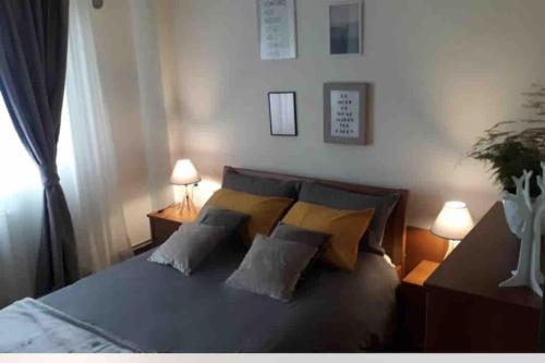 a bedroom with a bed with pillows and two lamps at The Grey Apartment - Center of Prishtina in Pristina