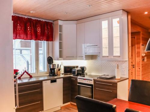 a kitchen with white cabinets and a red curtain at Holiday Home Lampitaival 6b by Interhome in Kotila