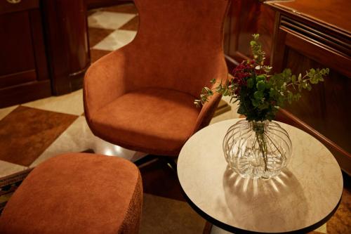 a vase of flowers on a table next to a chair at Duodo Palace in Venice