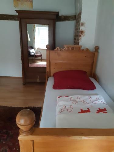 a bedroom with a wooden bed with a red pillow at Ales Ursula Sokolowski in Zerf