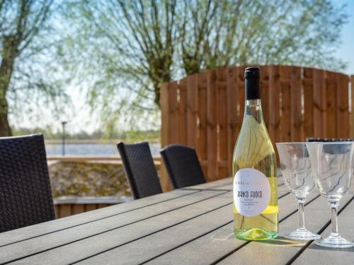 Una botella de vino sentada en una mesa de madera con dos copas en Holiday Home Gabija - all inclusive - in Western Jutland by Interhome en Højer
