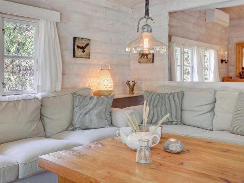 a living room with white couches and a wooden table at Holiday Home Solfred - 200m from the sea in Bornholm by Interhome in Vester Sømarken