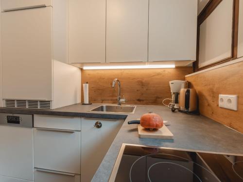 a kitchen with white cabinets and a pumpkin on a cutting board at Apartment Alpenpanorama by Interhome in Bad Gastein