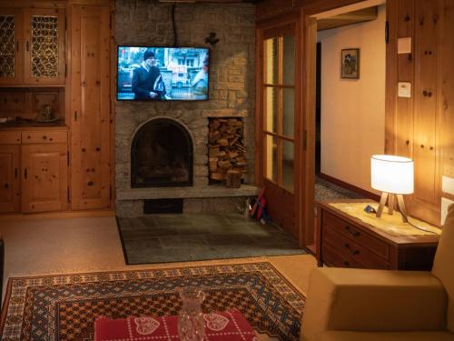 een woonkamer met een stenen open haard en een tv bij Apartment Chalet Turquino - Apartment Marmotte by Interhome in Zermatt