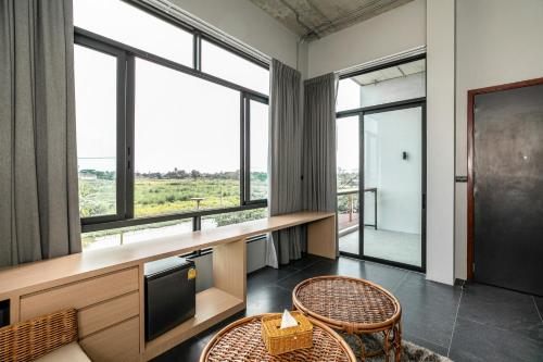 a room with a table and chairs and windows at Chainam-Charmchuree residences cafe and spa in Ban Bang Bua Thong