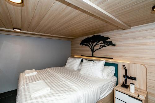 a bedroom with a bed with a tree on the wall at Chainam-Charmchuree residences cafe and spa in Ban Bang Bua Thong