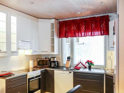 a kitchen with white cabinets and a red curtain at Holiday Home Lampitaival 6a by Interhome in Kotila