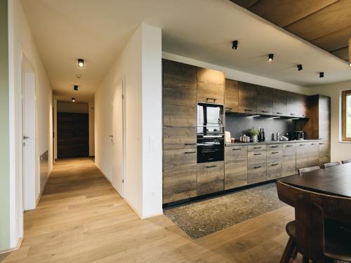 une grande cuisine avec des placards en bois et une table dans l'établissement Apartment Wulfenia Lodge 4 Raum IN2 by Interhome, à Sonnenalpe Nassfeld