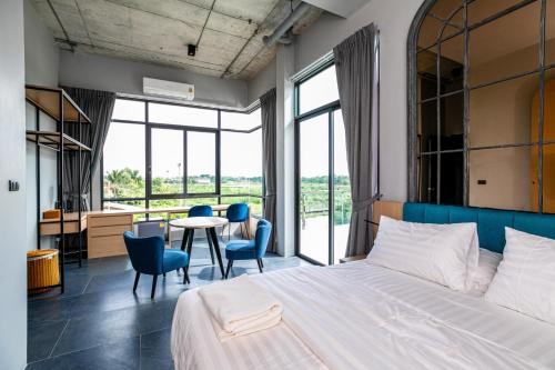 1 dormitorio con 1 cama, mesa y sillas en Chainam-Charmchuree residences cafe and spa en Ban Bang Bua Thong