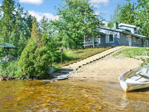 een huis aan de oever van een rivier met een boot bij Holiday Home Ilotupa by Interhome in Pertunmaa