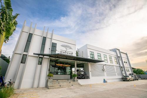 a large white building with a palm tree at Chainam-Charmchuree residences cafe and spa in Ban Bang Bua Thong