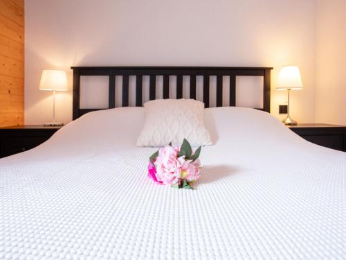 a pink flower on a white bed with two lamps at Chalet Chalet Les Pars by Interhome in Gryon