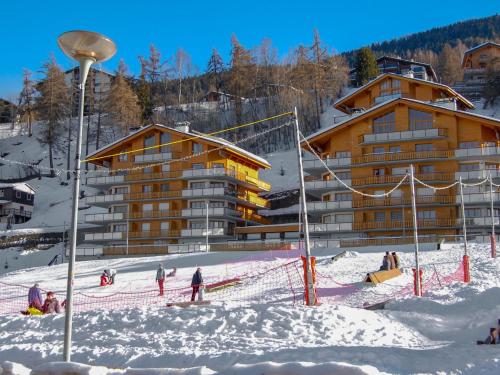 a group of people skiing in the snow in front of a building at Apartment Domaine des Reines A9 by Interhome in Nendaz