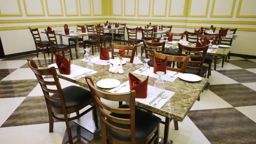 a dining room with tables and chairs with red napkins at Muscat International Hotel Plaza in Salalah