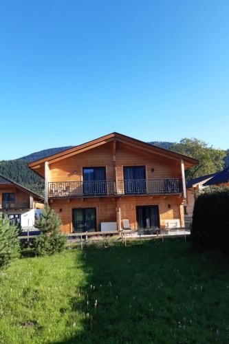 a large wooden house with a balcony and a yard at Holiday Home Alpenchalets Nassfeld-Rattendorf-2 by Interhome in Jenig
