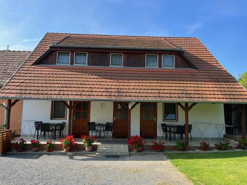 a house with a roof with tables and chairs at Ibolya Vendégház in Kehidakustány