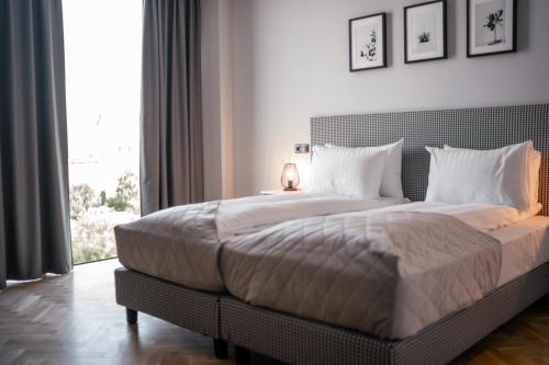 - une chambre avec un grand lit et une grande fenêtre dans l'établissement Hermanns Hotel & Spa Sibiu, à Sibiu