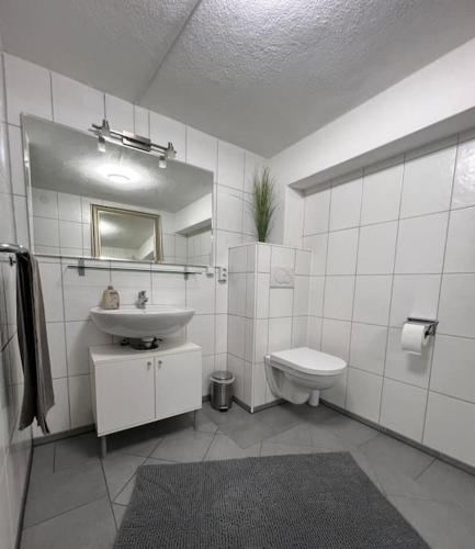 a white bathroom with a sink and a toilet at Ferienwohnung Rösler in Niederfüllbach