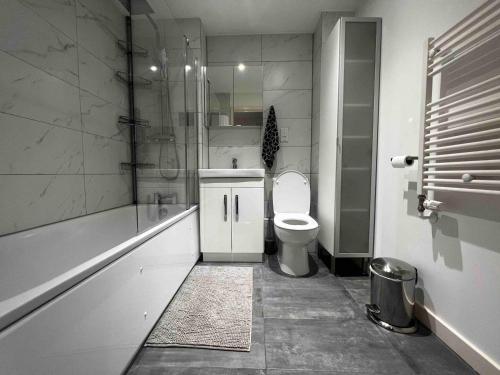 a bathroom with a toilet and a shower and a sink at Stylish 1-Bed Flat with Sofa-Bed in London in London