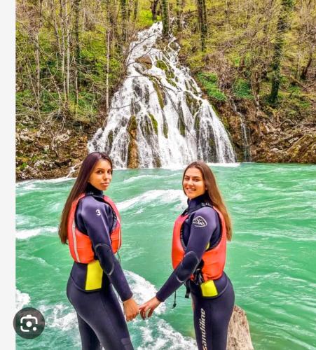 two women holding hands in front of a waterfall at Ethno village & resort Ćorić in Mojkovac