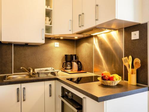 - une cuisine avec des placards blancs et un bol de fruits sur le comptoir dans l'établissement Apartment Beija Flor by Interhome, au Cap d'Agde