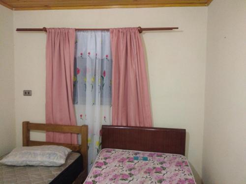 1 dormitorio con 1 cama y una ventana con cortinas rosas en casa familiar, en Guangualí