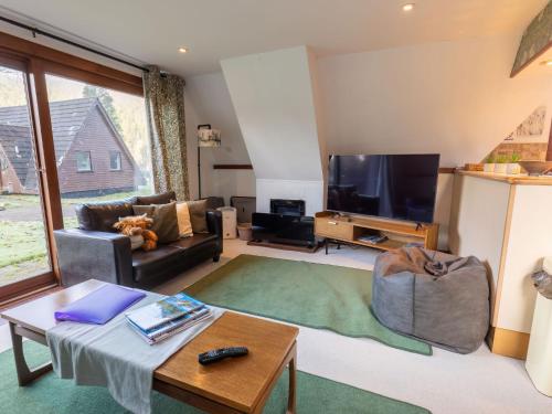 a living room with a couch and a tv at Chalet Caledonia Lodge by Interhome in Spean Bridge