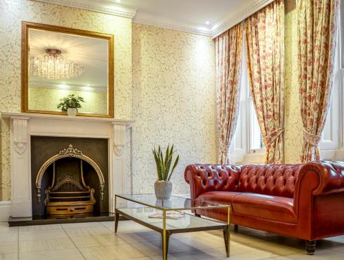 a living room with a red couch and a fireplace at Athena Hotel in London