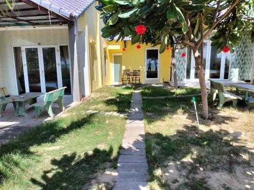 a house with benches and a tree in the yard at Biển Ngọc Homstay in Ấp Sung Xuân