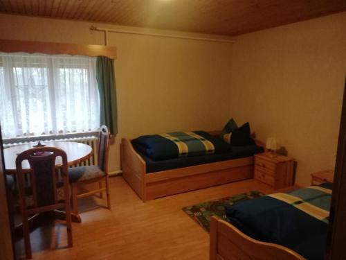 a bedroom with a bed and a table and a window at Gästezimmer an der Loipe in Bienenmühle