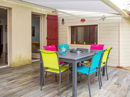 une table avec des chaises colorées sur une terrasse dans l'établissement Holiday Home Rive Droite by Interhome, à La Bernerie-en-Retz