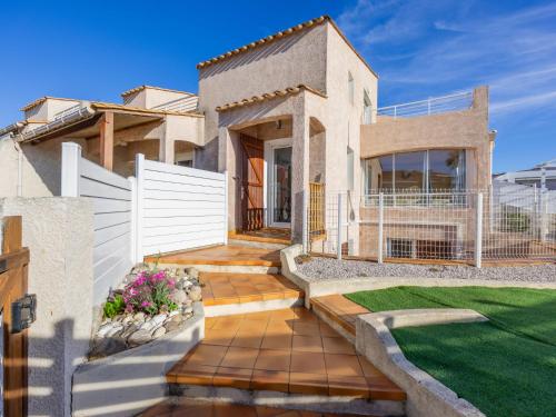 une maison avec une clôture blanche et une cour dans l'établissement Holiday Home Rochelongue by Interhome, au Cap d'Agde