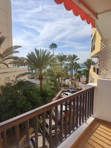 a balcony with a view of the beach and palm trees at Precioso estudio en Los Cristianos in Los Cristianos