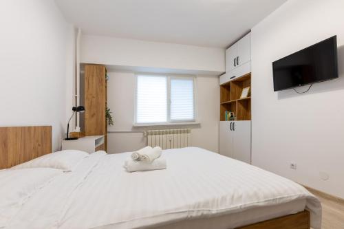 - une chambre avec un grand lit blanc et une télévision à écran plat dans l'établissement Minerva Studio Craiova, à Craiova