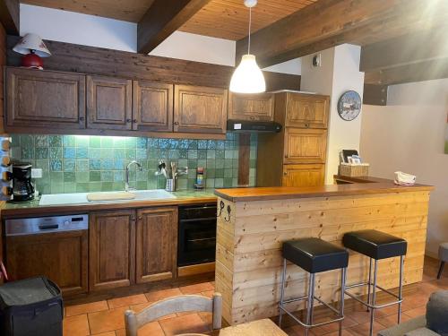 une cuisine avec des armoires en bois et un comptoir avec des tabourets dans l'établissement Apartment Clos du Chantey Moury by Interhome, à Chamonix-Mont-Blanc