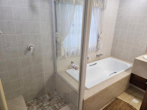 a bathroom with a tub and a shower with a shower curtain at Aleia Cottage in Pretoria