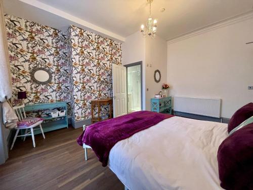a bedroom with a large bed with a purple blanket at LilyRose Hotel in Whitby